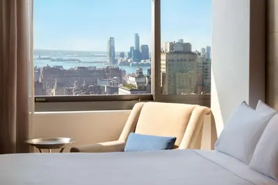 a bed and a chair in a room with a window at Hilton New York Times Square in New York