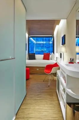 a small room with a bed and a red chair at citizenM New York Times Square in New York
