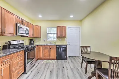 a kitchen with wooden cabinets and a table and a dining room at Philly Townhome with Gas Grill about 5 Mi to Dtwn! in Philadelphia