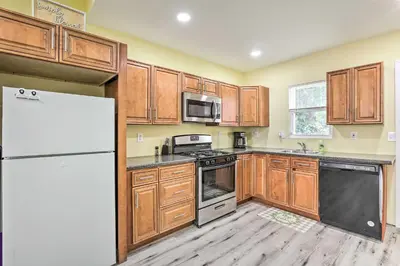 a kitchen with wooden cabinets and a white refrigerator at Philly Townhome with Gas Grill about 5 Mi to Dtwn! in Philadelphia