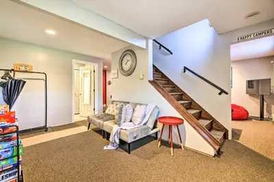 a living room with a couch and a staircase at Walk to Lake Game Room Getaway in Pocono Summit! in Pocono Summit