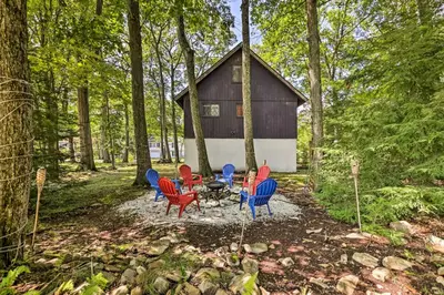 a group of chairs and a table in front of a cabin at Walk to Lake Game Room Getaway in Pocono Summit! in Pocono Summit