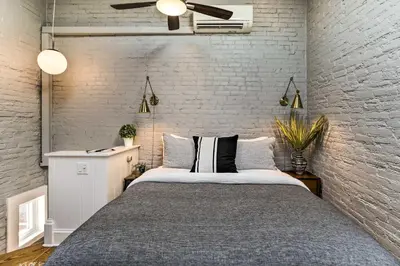 a bedroom with a bed and a white brick wall at Historic Home with Garden Walk to Center City! in Philadelphia