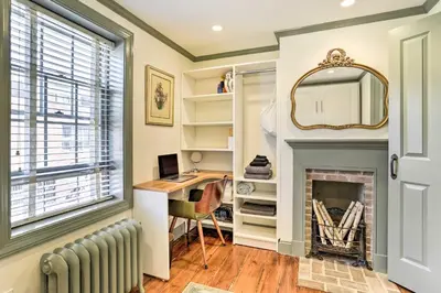 a room with a fireplace and a desk and a mirror at Historic Home with Garden Walk to Center City! in Philadelphia