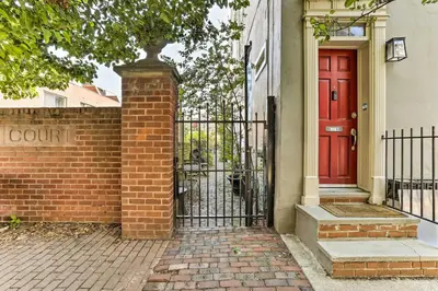 a red door on a brick house with a gate at Historic Home with Garden Walk to Center City! in Philadelphia