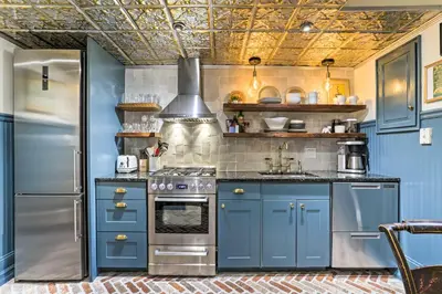 a kitchen with blue cabinets and a stainless steel refrigerator at Historic Home with Garden Walk to Center City! in Philadelphia