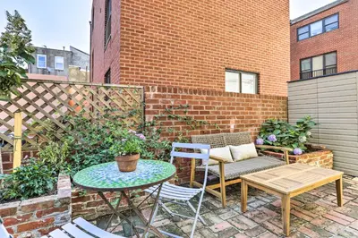 a patio with a table and chairs and a brick wall at Historic Home with Garden Walk to Center City! in Philadelphia
