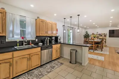 a kitchen with wooden cabinets and a dining room at Game Room and Yard Family Paradise in Pocono Summit in Pocono Summit Estates