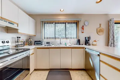 a kitchen with white cabinets and a sink at House in the Woods in Albrightsville