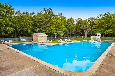 a large swimming pool with chairs and trees at House in the Woods in Albrightsville