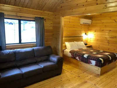 a bedroom with a couch and a bed in a log cabin at Lakewood Park Campground - Luxury Cabin in Barnesville