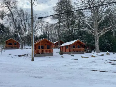 a group of wooden cabins in the snow at Lakewood Park Campground - Luxury Cabin in Barnesville