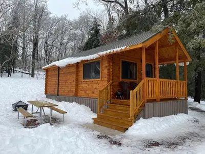 a wooden cabin with a picnic table in the snow at Lakewood Park Campground - Luxury Cabin in Barnesville