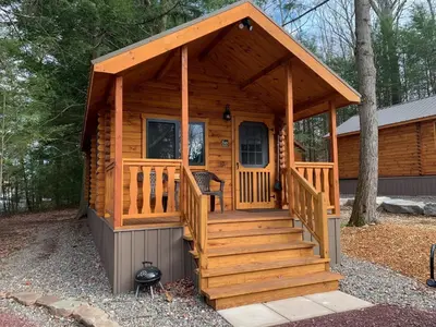 a log cabin with a large porch and stairs at Lakewood Park Campground - Luxury Cabin in Barnesville