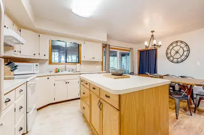 a kitchen with white cabinets and a dining room at The Cabin in Pocono Summit