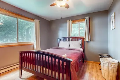 a bedroom with a crib and two windows at The Cabin in Pocono Summit