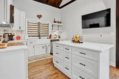 a kitchen with white cabinets and a tv on the wall at Chimney Hill Estate Inn in Lambertville