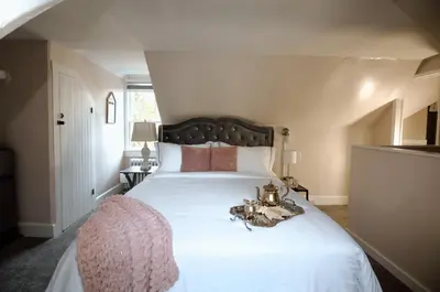 a bedroom with a large bed with white sheets and pink pillows at Chimney Hill Estate Inn in Lambertville