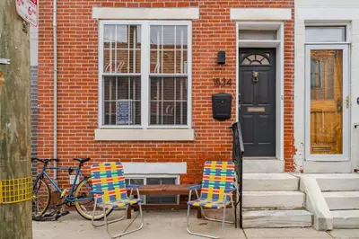 two chairs sitting outside of a house with a door at Bedroom in thoughtfully decorated East Passyunk home (South Philadelphia) in Philadelphia