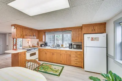 a kitchen with wooden cabinets and a white refrigerator at Amish Country Apartment with Cozy Fireplace! in New Holland