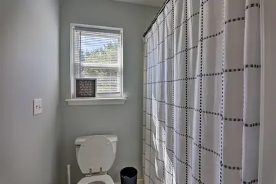 a bathroom with a white toilet and a window at Hot Tub, Fire Pit and Lake Access Poconos Escape! in Albrightsville
