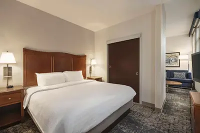 a bedroom with a large white bed and a living room at Hampton Inn Manhattan/Downtown- Financial District in New York