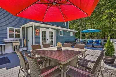 a patio with a wooden table and a red umbrella at Stunning South Fallsburg Home with Pool and Deck! in South Fallsburg