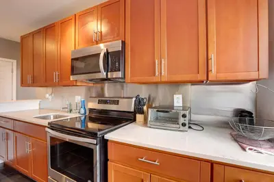 a kitchen with wooden cabinets and a stove and microwave at Philadelphia Apartment, Near Transit and Sites! in Philadelphia