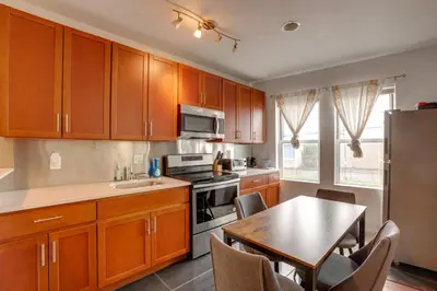 a kitchen with wooden cabinets and a table with chairs at Philadelphia Apartment, Near Transit and Sites! in Philadelphia
