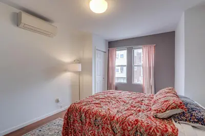 a bedroom with a bed with a red comforter and a window at Philadelphia Apartment, Near Transit and Sites! in Philadelphia