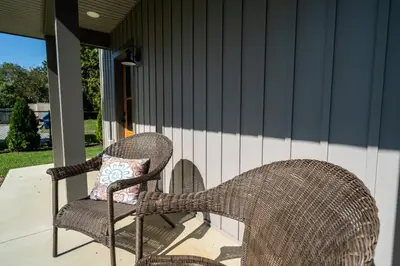 two wicker chairs sitting on a porch with a pillow at A newly built Tiny House in the center of Historic Kennett Square in Kennett Square