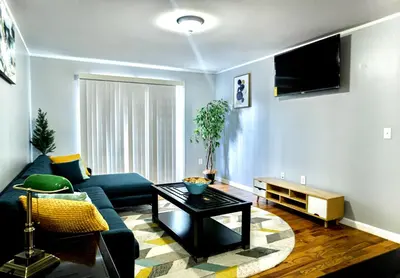 a living room with a blue couch and a table at Urban Oasis Spacious 3BR 2BA Patio Near NYC EWR American Dream Mall in Newark