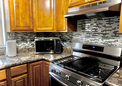 a kitchen with a stove and a microwave at Urban Oasis Spacious 3BR 2BA Patio Near NYC EWR American Dream Mall in Newark