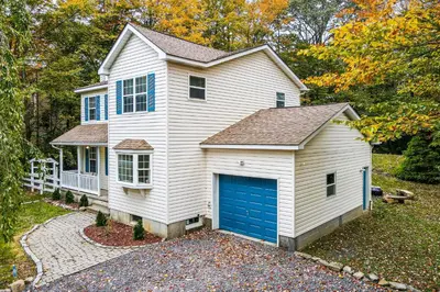 a white house with a blue garage at Tree and Easy in Tobyhanna