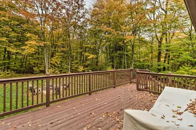 a deck with a chair and a view of the woods at 12 Mi to Camelback Ski Resort Home with Decks! in Tobyhanna