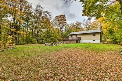 a house in the middle of a yard with leaves on the ground at 12 Mi to Camelback Ski Resort Home with Decks! in Tobyhanna