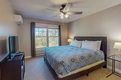 a bedroom with a bed with a ceiling fan and a window at Northridge Retreat in Tannersville