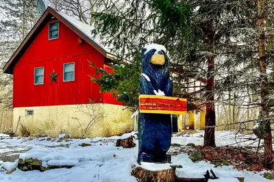 a statue of a bear in the snow in front of a red barn at Deck and Forest Views Secluded Cresco Cabin! in Cresco