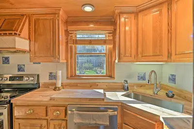 a kitchen with wooden cabinets and a sink and a window at Unadilla Cabin on 50 Acres and Fire Pit and Creek in Unadilla