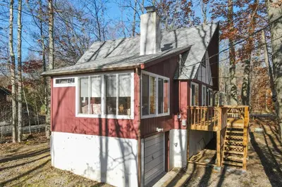 a red and white tiny house in the woods at Arrowhead Lake Leisure in Pocono Lake