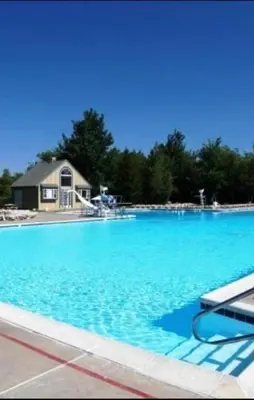 a large swimming pool with a house in the background at Pocono House in a private community 4 pools, Lake. in Tobyhanna