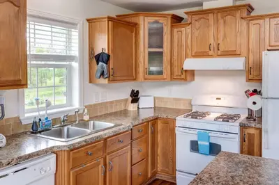 a kitchen with wooden cabinets and a white stove top oven at Bluestone Hill House in Walton