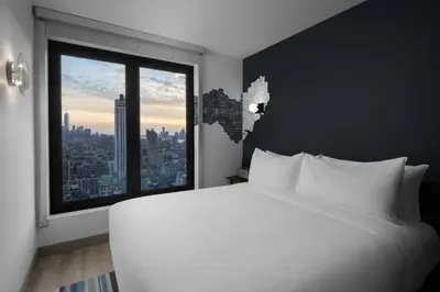 a bedroom with a large white bed and a large window at Aloft New York Chelsea in New York