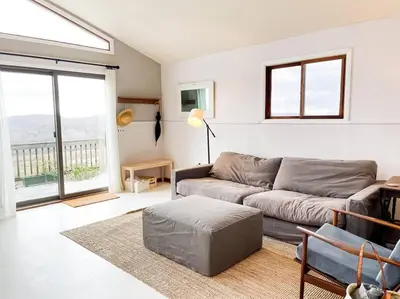 a living room with a couch and a large window at Hamden Hill House in Hamden