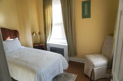 a bedroom with a bed and a chair and a window at Lincoln Manor - Newly Renovated, 1mile from PHL Airport and Sports Stadiums in Prospect Park