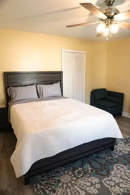 a bedroom with a bed with a ceiling fan and a chair at Lincoln Manor - Newly Renovated, 1mile from PHL Airport and Sports Stadiums in Prospect Park