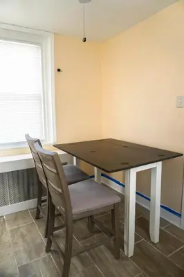 a dining room table with two chairs and a window at Lincoln Manor - Newly Renovated, 1mile from PHL Airport and Sports Stadiums in Prospect Park