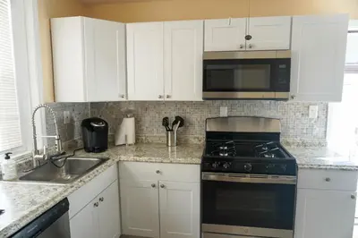a kitchen with white cabinets and a stove and a sink at Lincoln Manor - Newly Renovated, 1mile from PHL Airport and Sports Stadiums in Prospect Park