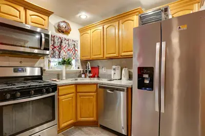a kitchen with wooden cabinets and stainless steel appliances at Newark Home with Deck and Fire Pit, 16 Mi to NYC! in Newark