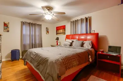 a bedroom with a red bed and a ceiling fan at Newark Home with Deck and Fire Pit, 16 Mi to NYC! in Newark